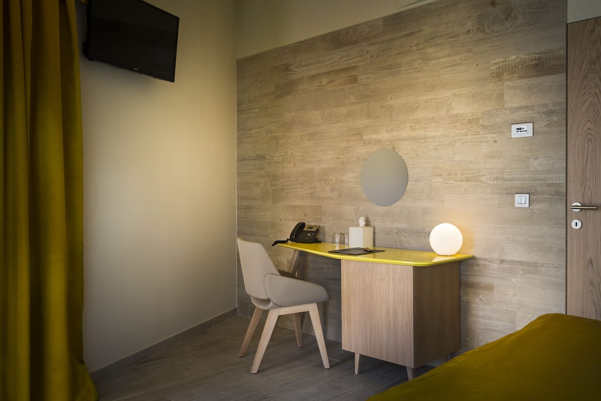 Habitación de hotel con una pared de acento de madera, un escritorio con teléfono y lámpara, una silla y una cama.
