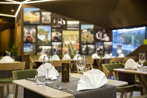 Interior de un restaurante con mesas dispuestas con cuidado, cada una con vaso, servilleta y cubiertos.