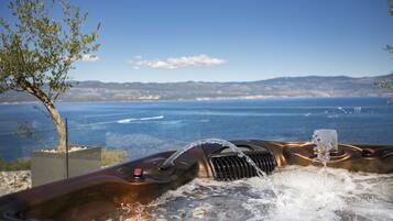 A hot tub with a view of the sea and mountains.