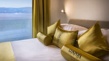 Una habitación de hotel con una cama, almohadas doradas y vista al mar.