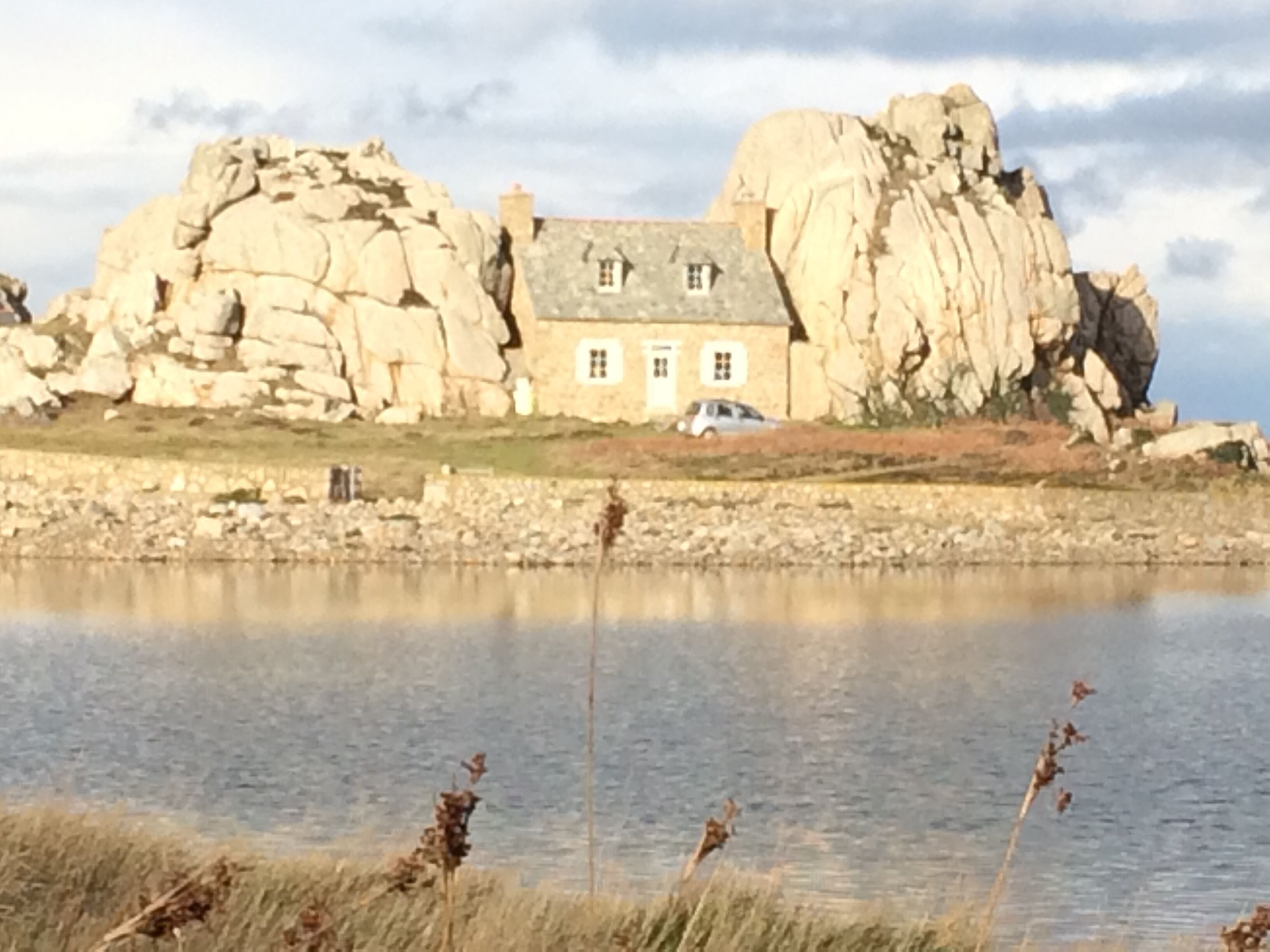 A house with a stone facade and a large rock formation nearby.