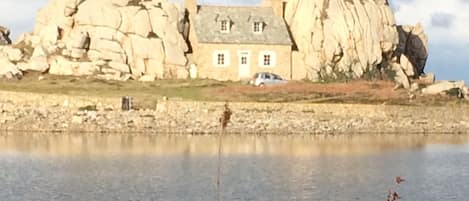 A house with a stone facade and a large rock formation nearby.