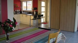 A modern kitchen with a dining area, featuring a striped rug, wooden chairs, and a view of the outside.