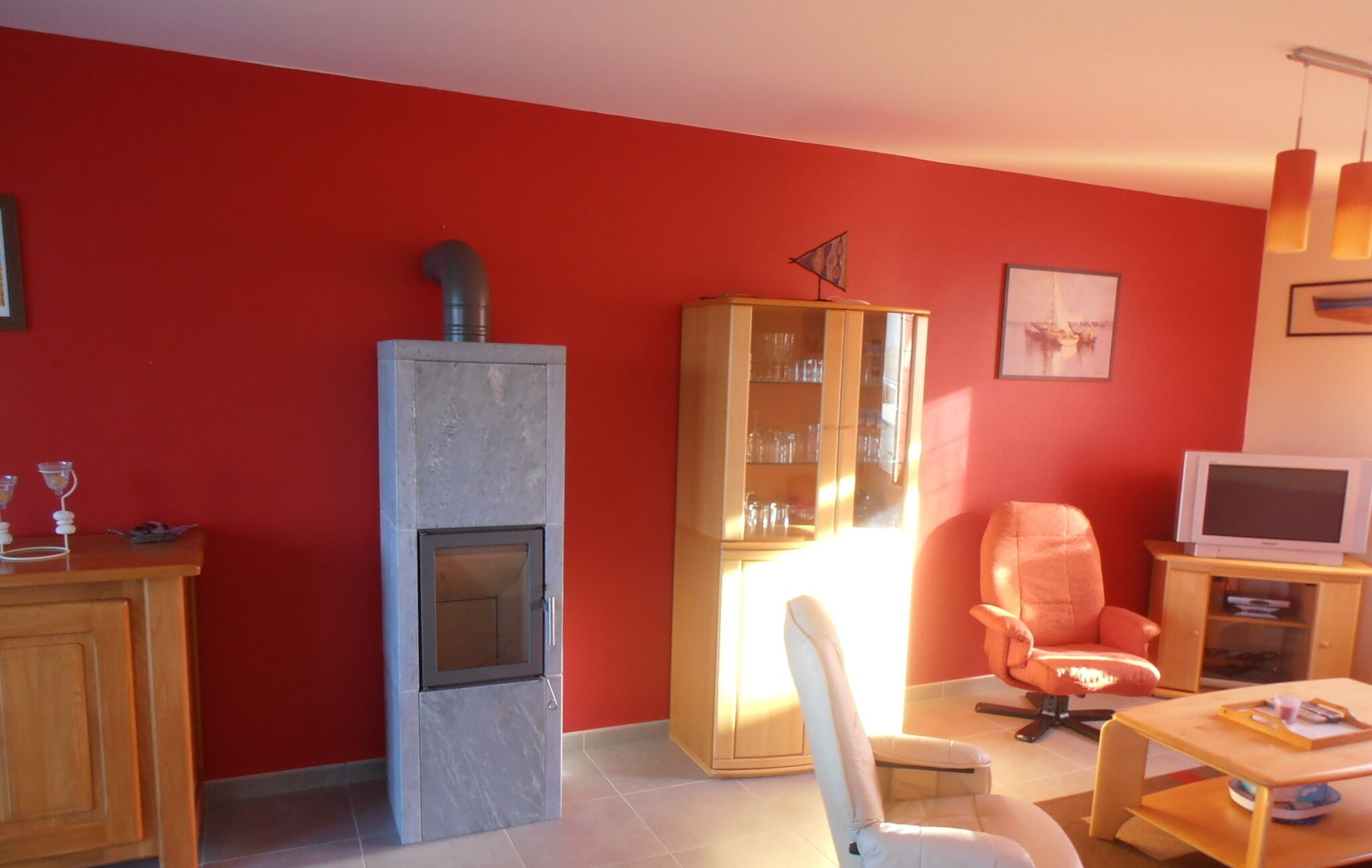 A living room with a fireplace, a glass cabinet, a chair, and a television.