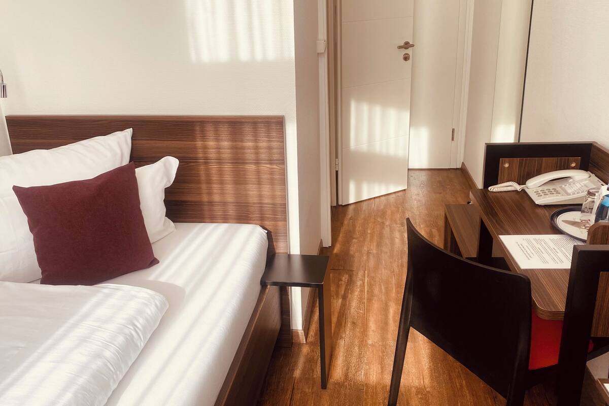 Una habitación de hotel con una cama, un escritorio y un teléfono, y una silla.