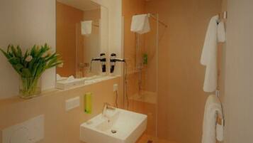 Un baño moderno con lavabo, espejo y ducha.