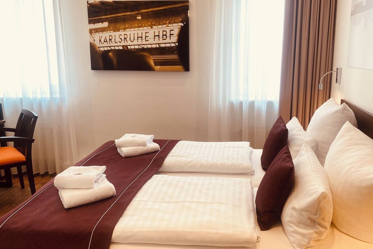 Una habitación de hotel con una cama bien hecha, una silla y un cartel en la pared.