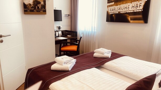 A hotel room with a bed, a desk, a chair, and a television. - sevenDays Hotel BoardingHouse (Karlsruhe)