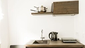 A compact kitchen with a wooden cabinet, a sink, a kettle, and a scale. - sevenDays Hotel BoardingHouse (Karlsruhe)