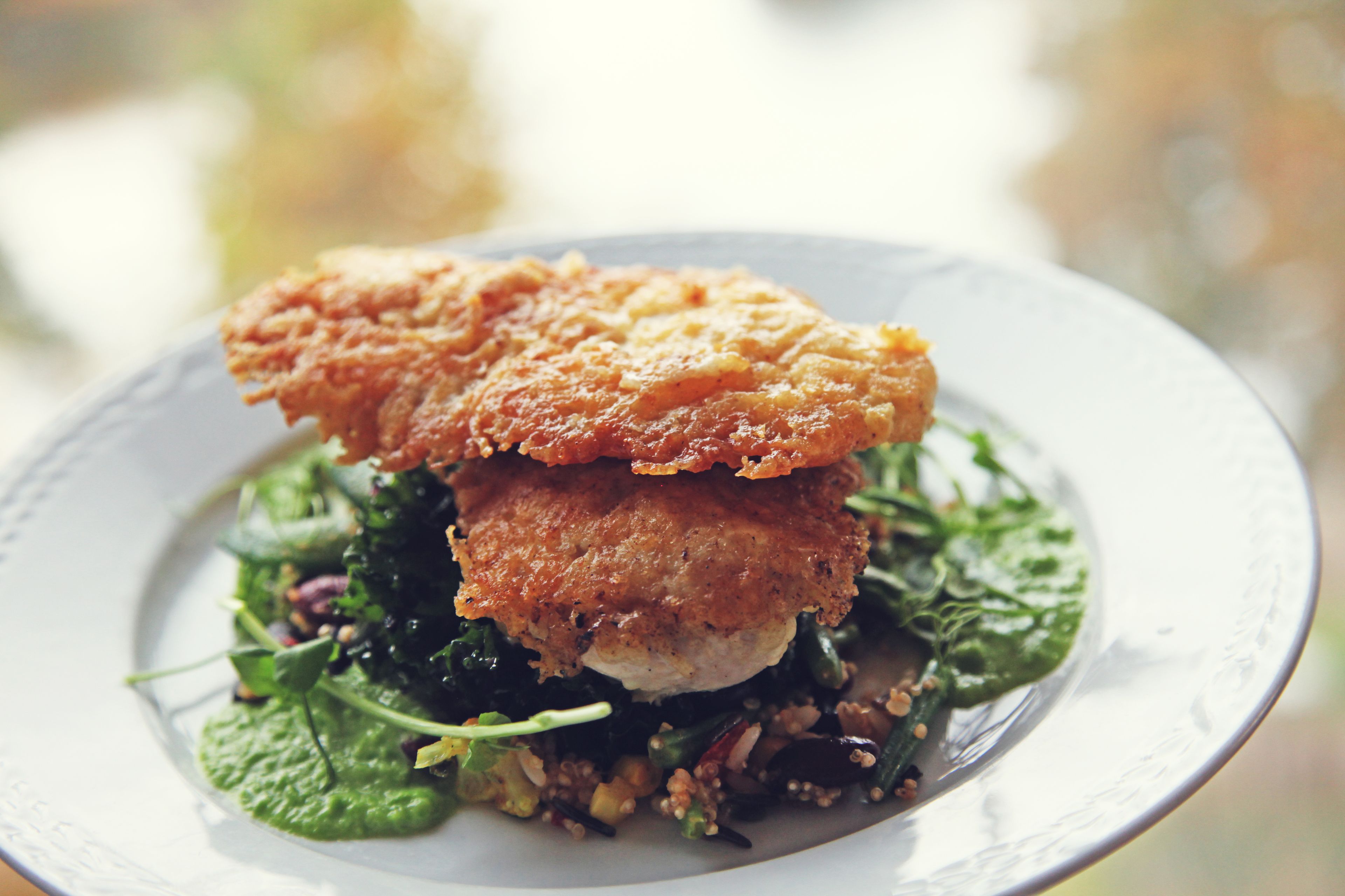 A plate with a piece of breaded chicken and greens.