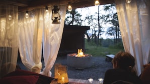 A cozy interior with a fire pit, candles, and a view of the outdoors. - Vårdnäs Stiftsgård (Brokind)