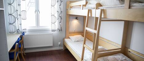 Habitación con literas, un escritorio, una silla, una ventana con cortinas y un radiador.