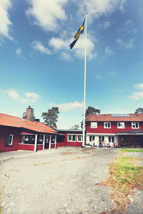 A building with a red facade and a flagpole with a flag. - Vårdnäs Stiftsgård (Brokind)