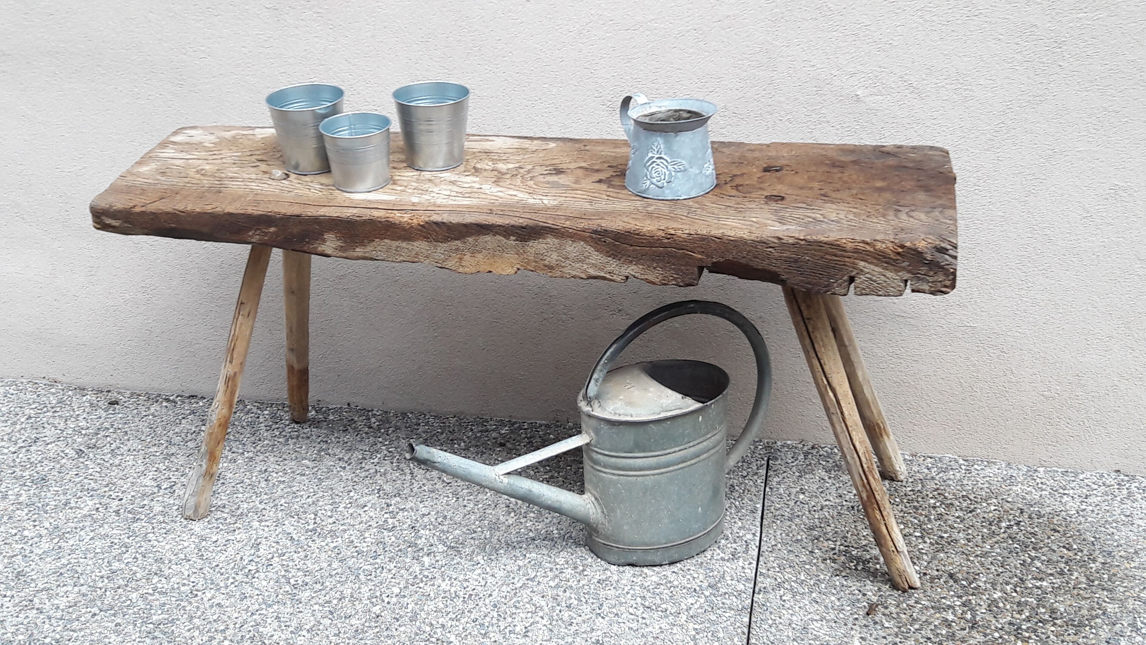 Una mesa de madera rústica con tazas y un cubo de metal.