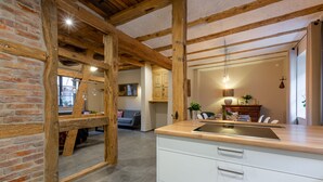Une cuisine avec des poutres apparentes, un mur en briques et un plan de travail moderne.