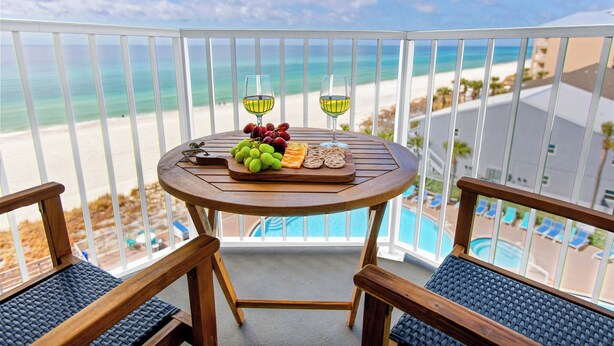 A balcony with a table set for a meal, overlooking a beach and pool. - TIDEWATER 4th FLOOR - SKIP ELEVATORS! No Windows on Hallway, walk to Pier Park! (Panama City Beach)