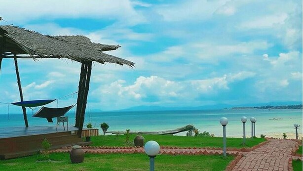 A beachside walkway with a thatched-roof structure and a hammock. - 9 Huts on a Hill (Kudat)