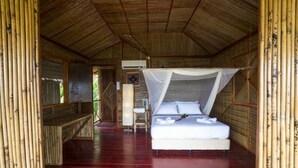 A room with a bed under a mosquito net, wooden walls, and a red floor. - 9 Huts on a Hill (Kudat)