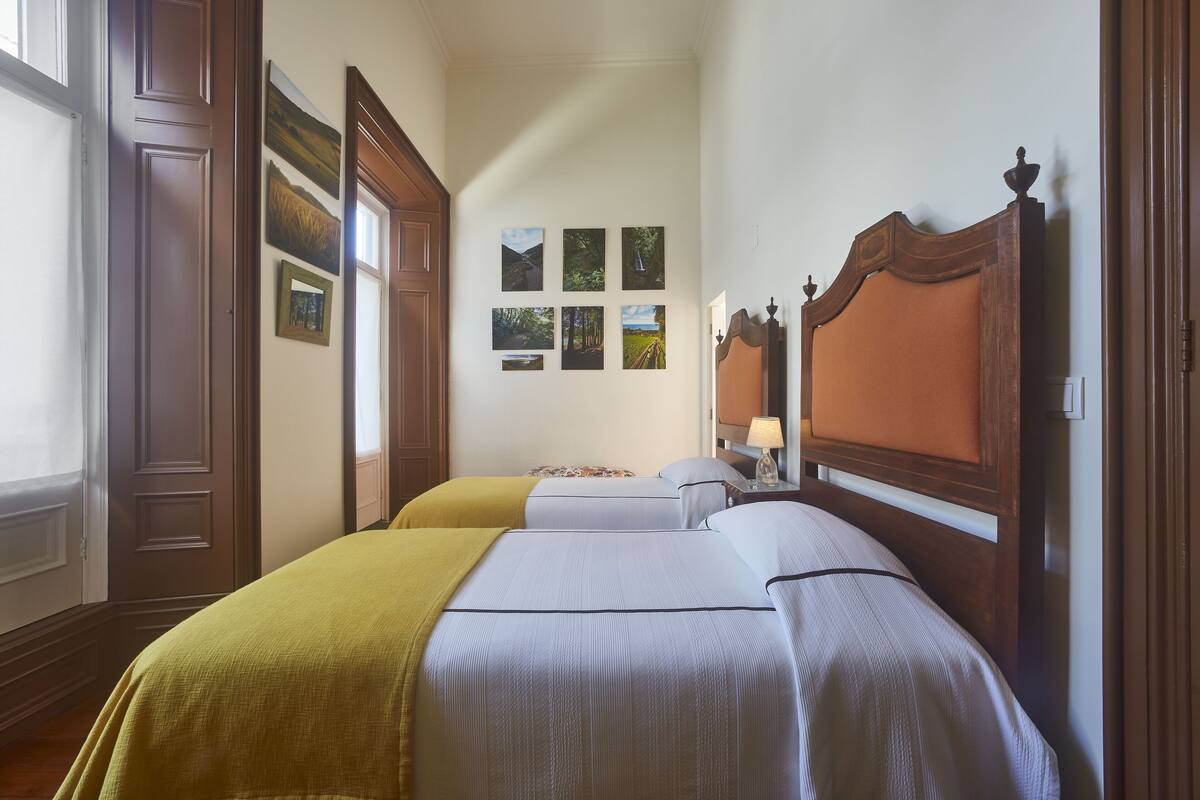 Ein Hotelzimmer mit zwei Betten, Holz-Kopfteilen und einer Wand mit gerahmten Bildern.