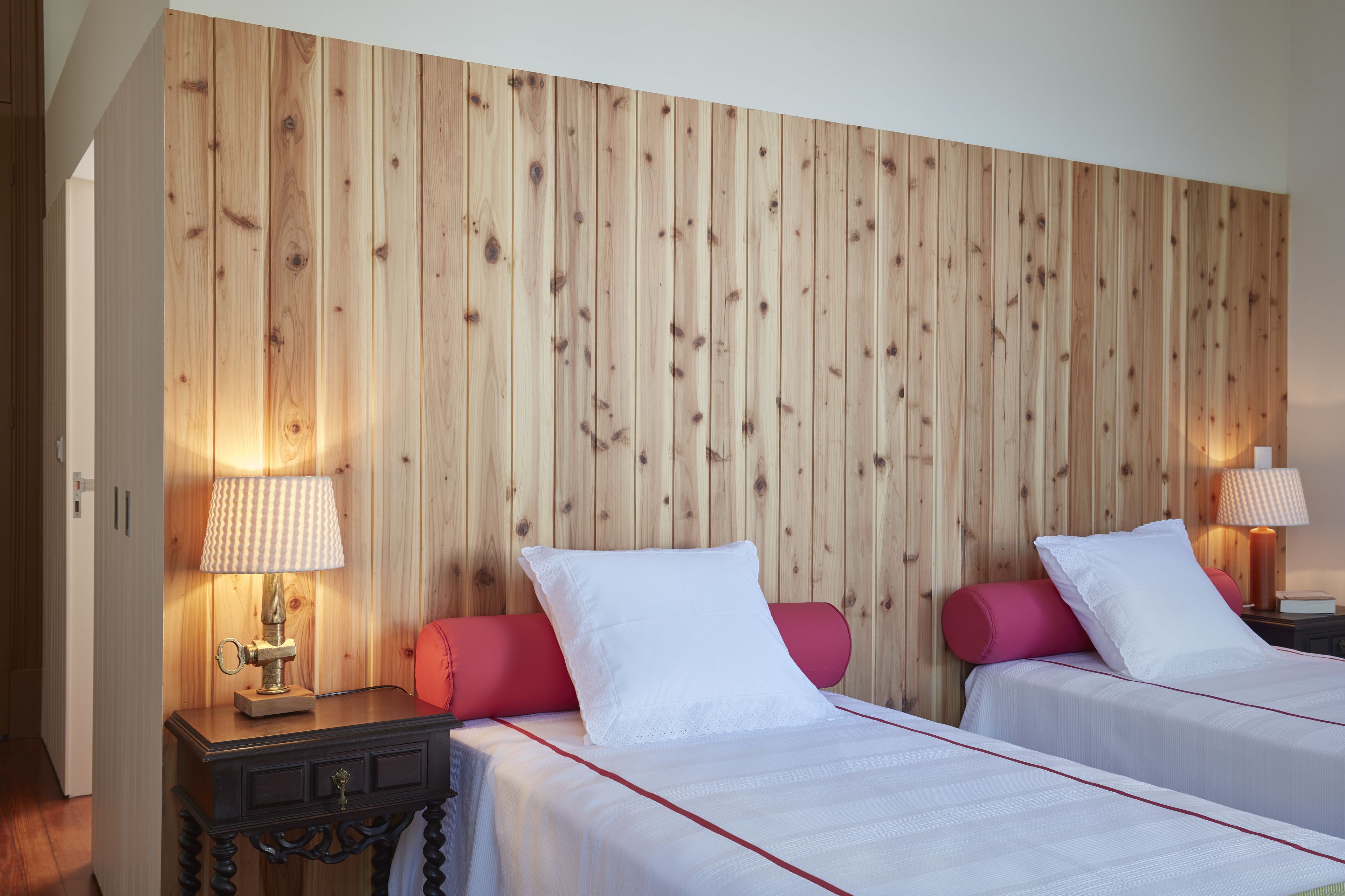 Ett hotellrum med två sängar, träpanel på väggen och sänglampor.