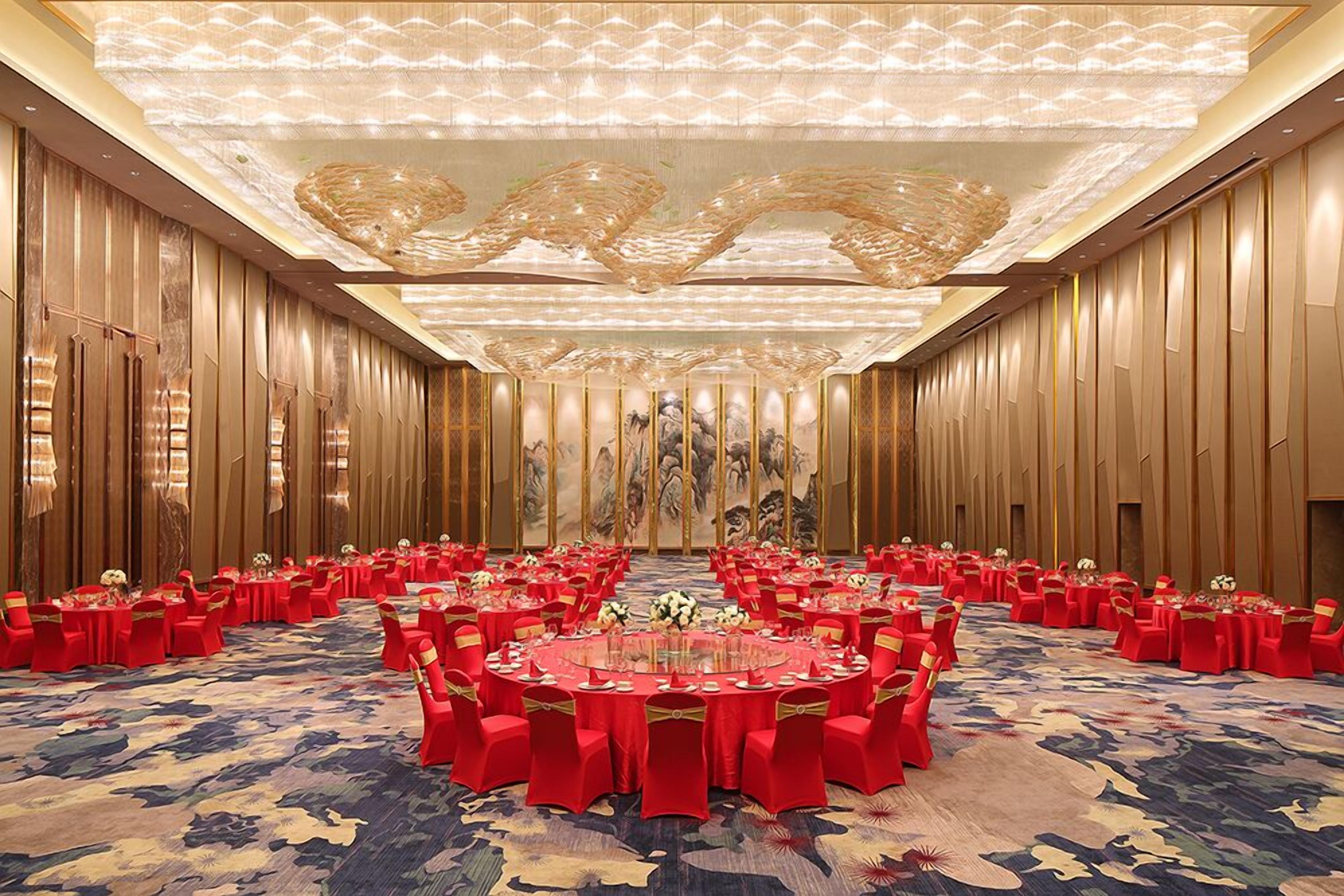 Une salle de conférence avec des tables rondes, des chaises rouges et un sol recouvert de moquette.