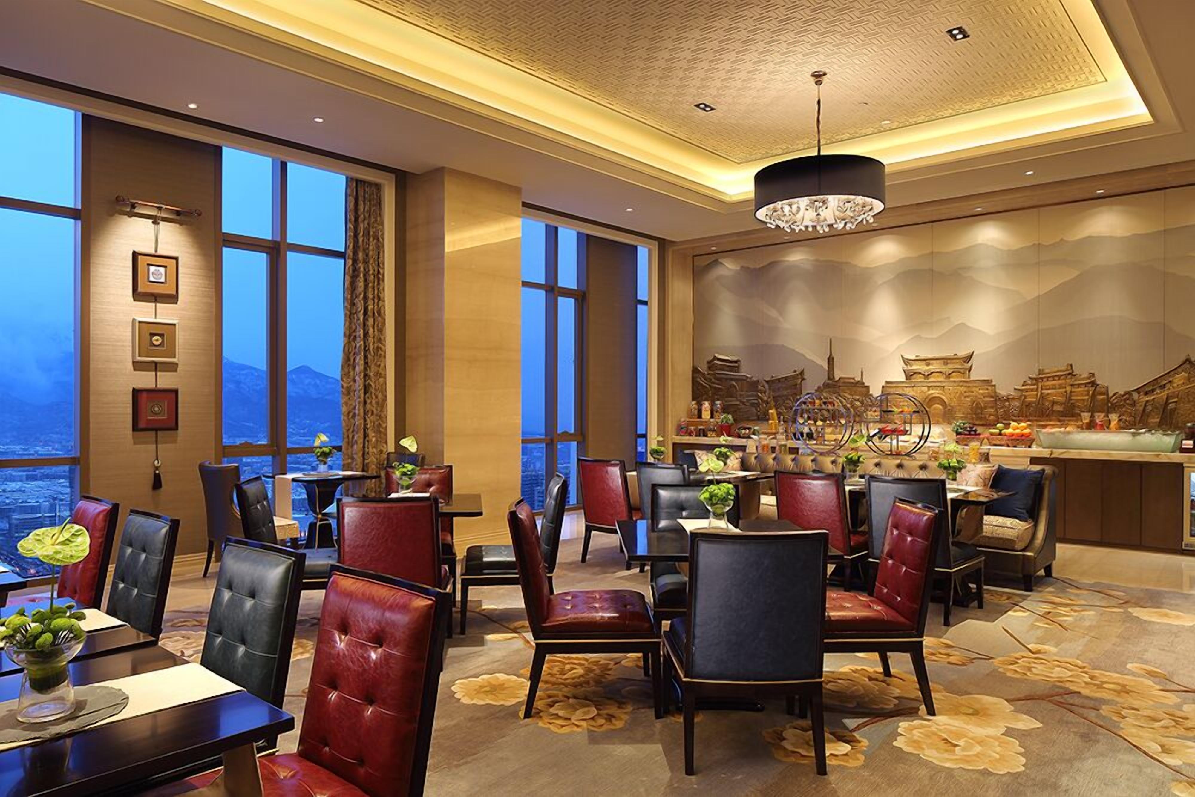 A hotel lobby with leather chairs, a bar area, and large windows offering a view of the cityscape.