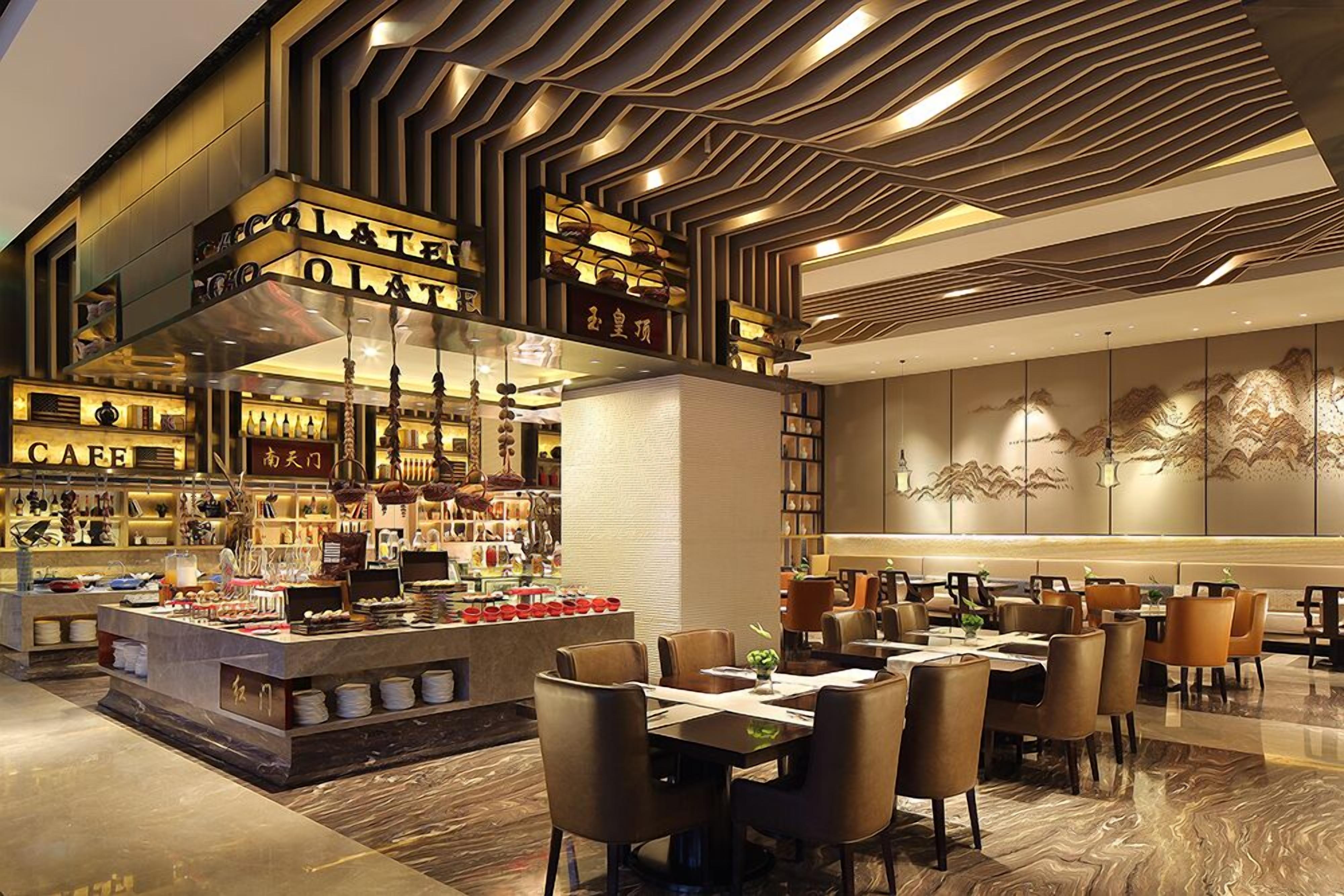 Restaurante moderno com ilha central, diversas áreas de estar e teto decorativo.