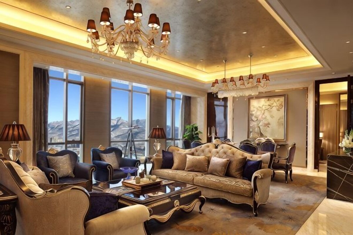 Un salón amplio con un sofá grande, sillones, una mesa de centro y una araña.