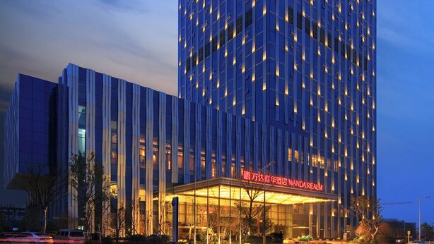 A high-rise hotel with a modern facade, illuminated windows, and a prominent entrance with signage. - Wanda Realm Taian (Tai'an)