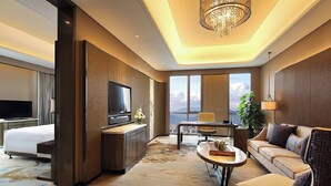 A modern hotel room with a large bed, a desk, a television, a sofa, and a view of the city. - Wanda Realm Taian (Tai'an)