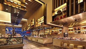 A modern hotel lobby with a central reception desk, multiple seating areas, and a variety of amenities including a food display and decorative items. - Wanda Realm Taian (Tai'an)