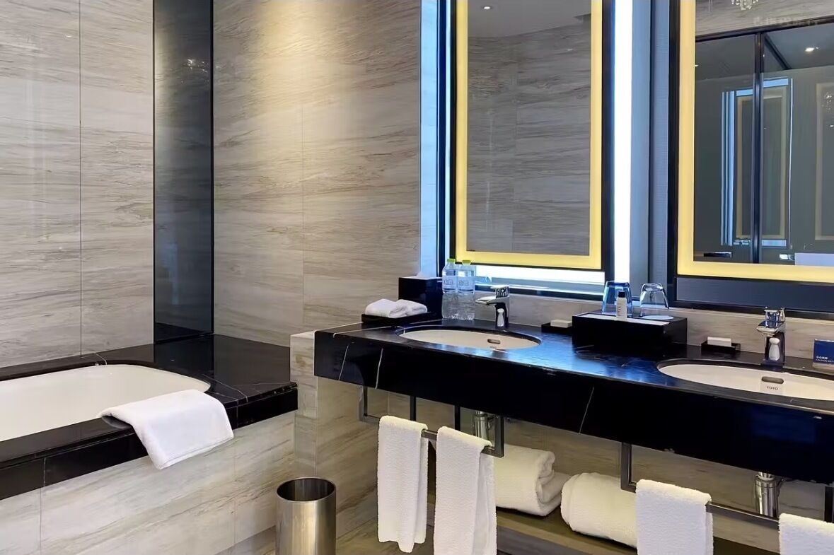 A modern bathroom with two sinks, a large mirror, and a bathtub.