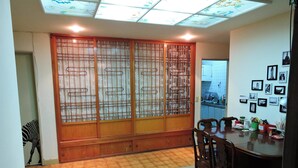 A dining area with a wooden table and chairs, a decorative screen, and a tiled floor. - Star House 2 (Taipei)