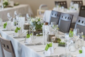 Una mesa de banquete dispuesta con cristalería, platos y servilletas, con un centro de mesa decorativo y una vela.