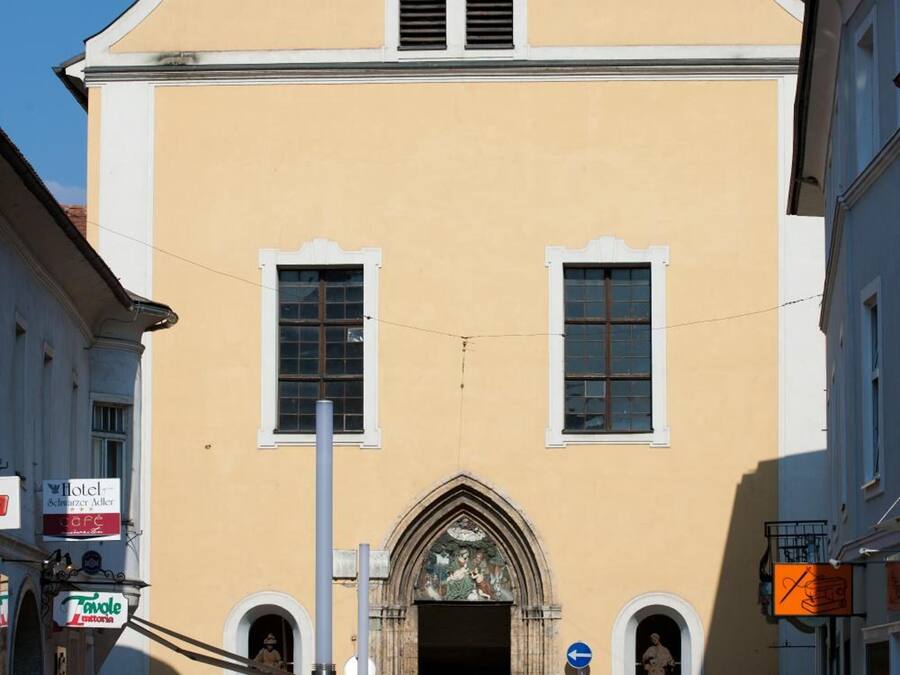 A building with a clock, a large arched entrance, and a sign for a cafe.