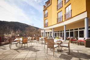 Un patio al aire libre con mobiliario de mimbre y vistas a la montaña.