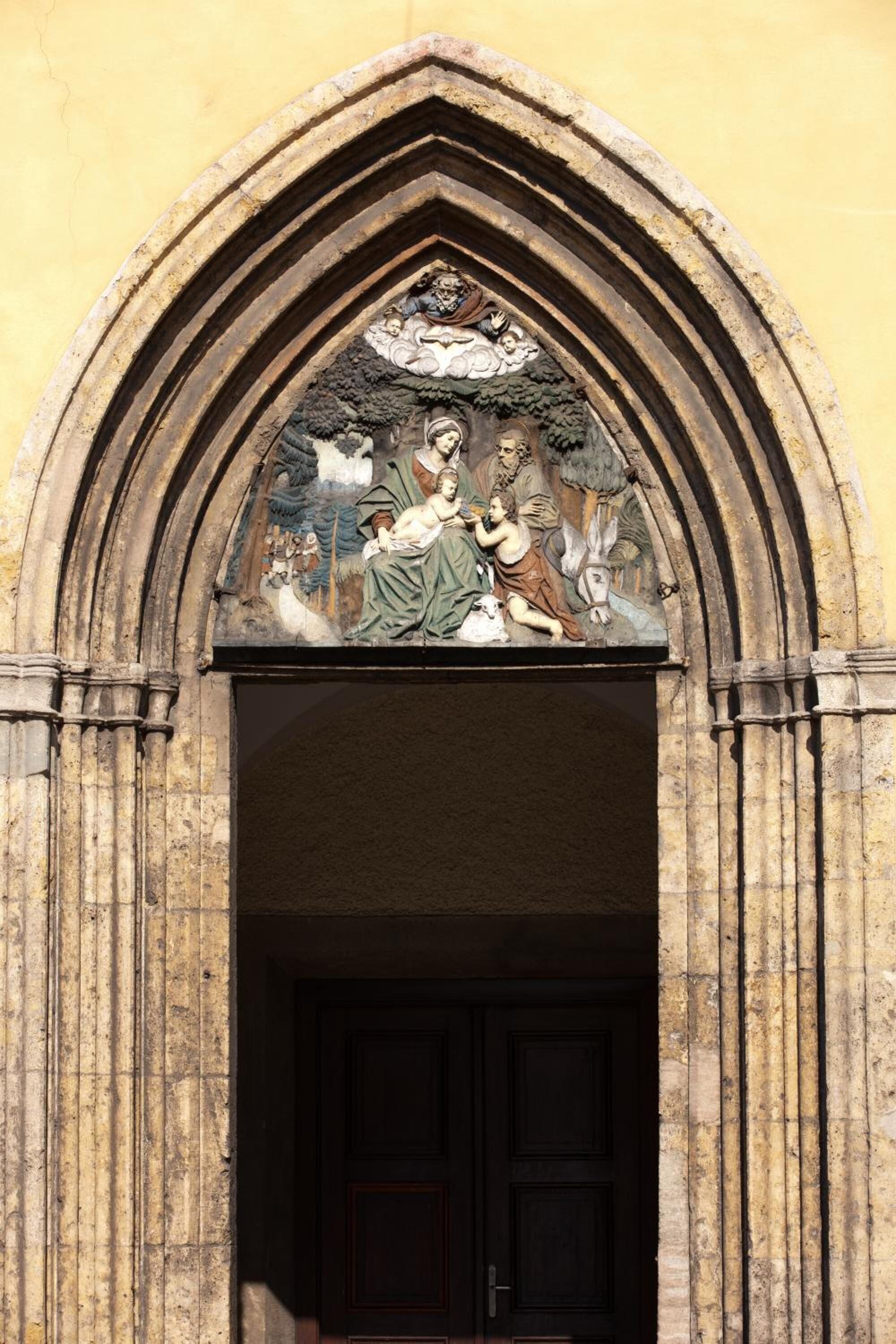 A doorway with a detailed stone arch and a relief sculpture above it.