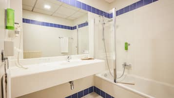 A bathroom with a white sink, a mirror, a glass-enclosed shower, and blue-tiled walls.