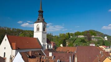 A church with a tall steeple and a clock tower, surrounded by buildings with red-tiled roofs.