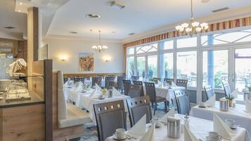 Un ristorante con diversi tavoli, sedie e un'area riservata al buffet.