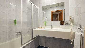 A bathroom with a bathtub, a sink with a mirror, and a telephone.