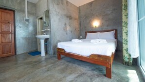 A bedroom with a wooden bed, a white sink, a mirror, and a door. - PK Resort (Sikao)