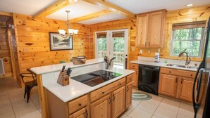 A wooden cabin kitchen with a central island, wooden cabinets, a dishwasher, and a refrigerator. - Secluded Mountain Haven in Seven Devils (Seven Devils)