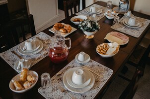 Una mesa de comedor dispuesta con diversos platos, incluyendo pasteles, pan y una jarrón de té.