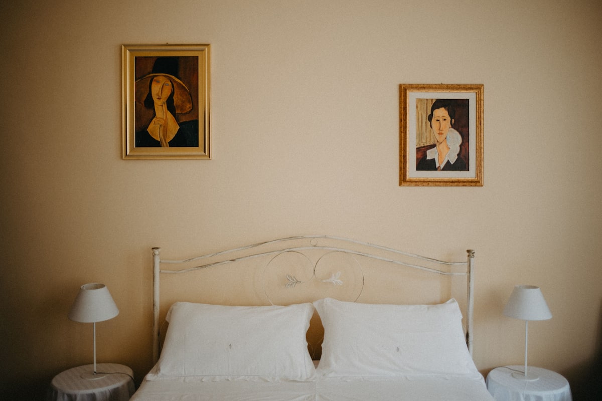 A bedroom with a bed, two bedside tables, and two framed pictures on the wall.