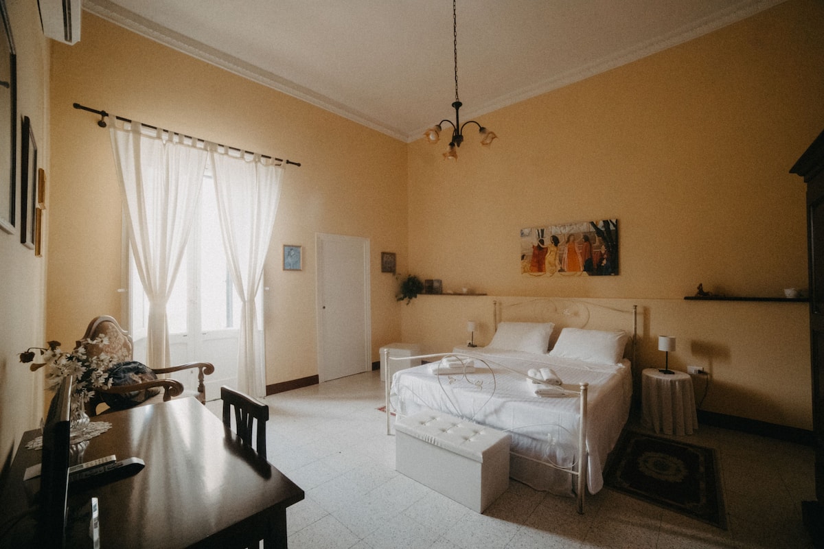 A bedroom with a bed, bedside table, and a painting on the wall.