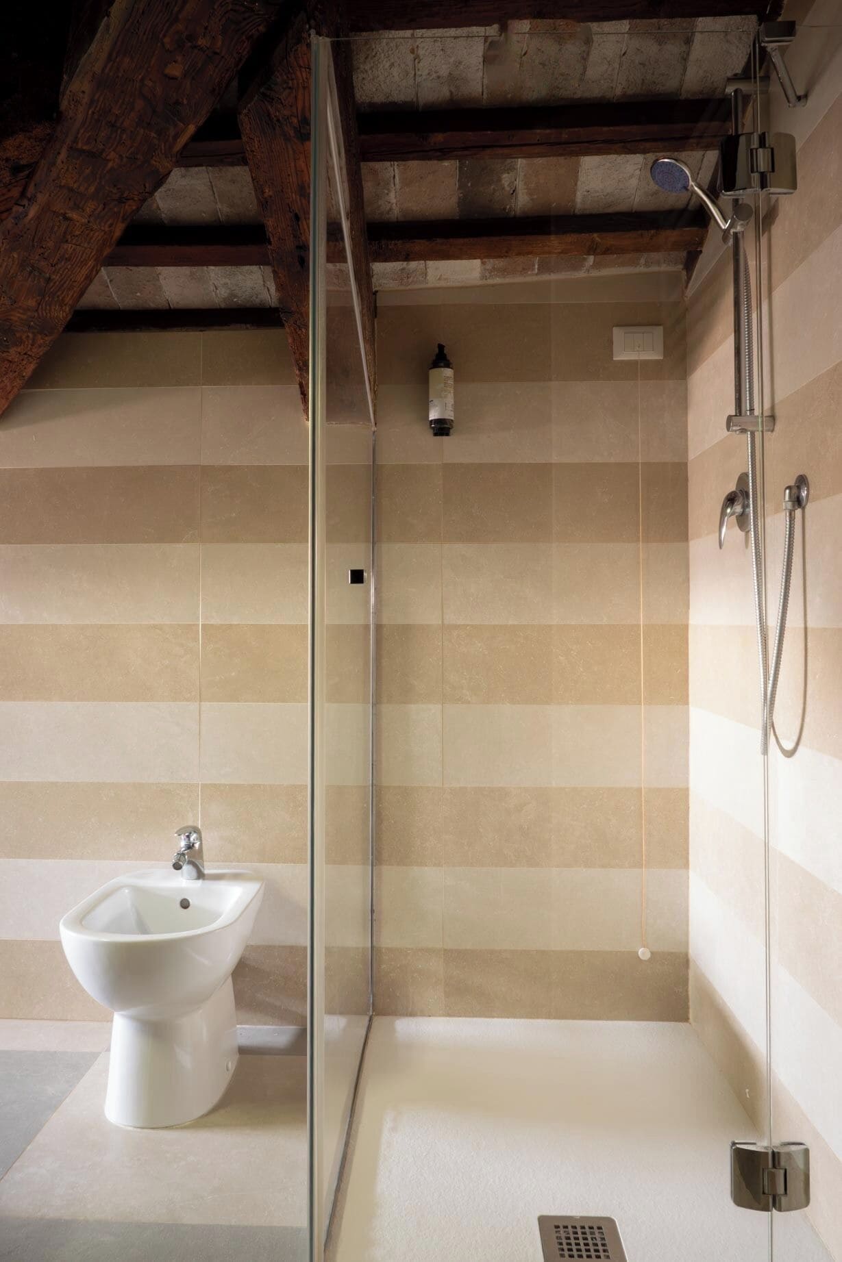 A modern bathroom with a glass shower enclosure, a pedestal sink, and a showerhead.