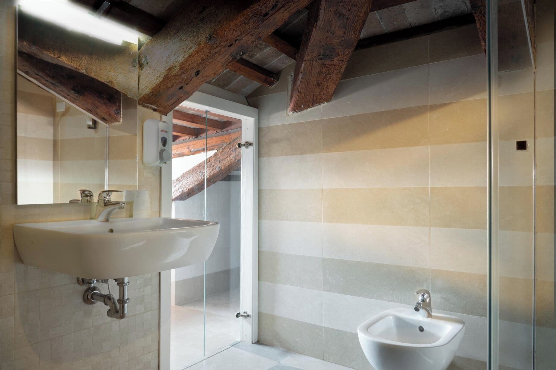A bathroom with a large sink, a bidet, and a glass shower enclosure.