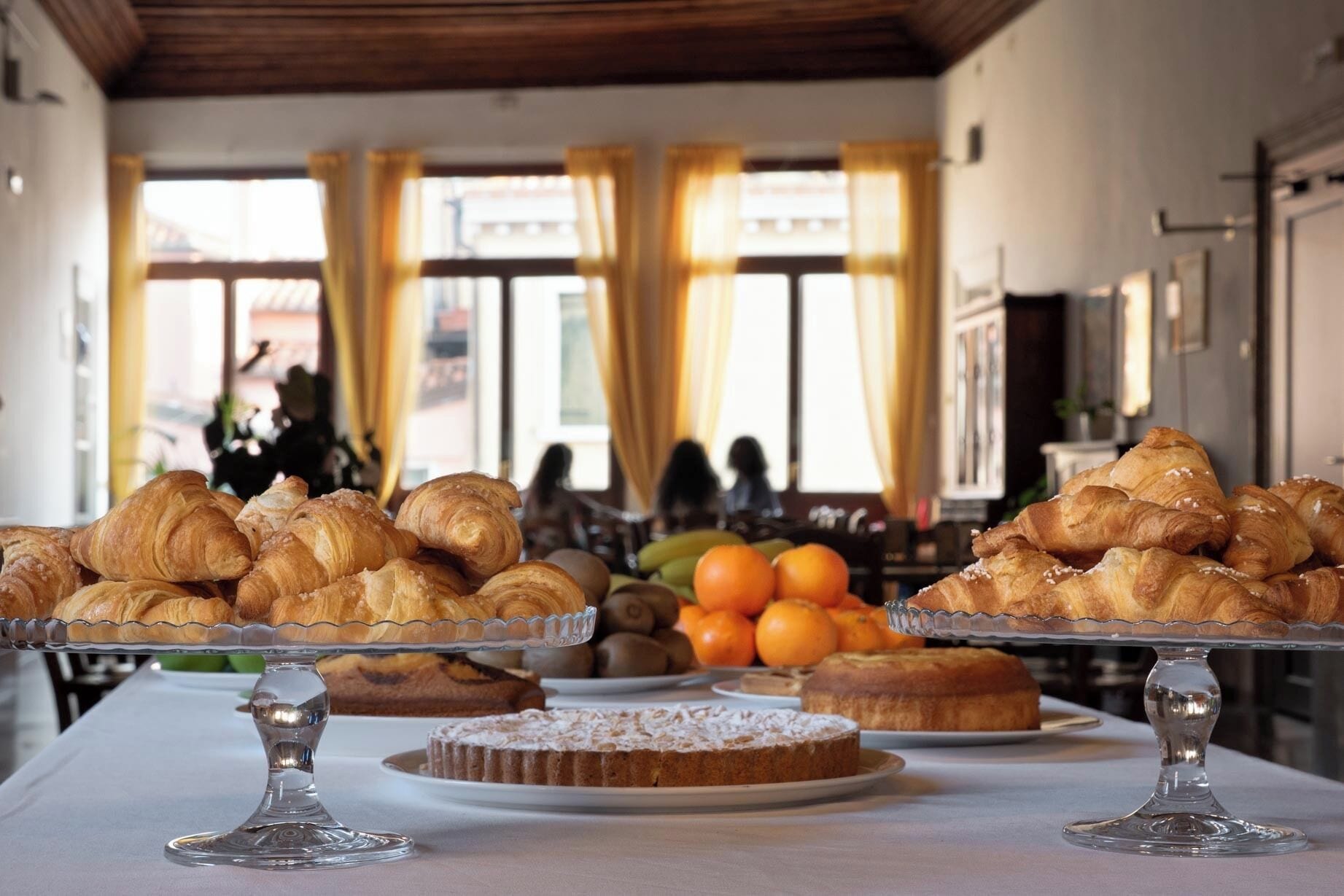 A buffet table with pastries, a cake, and fruits.