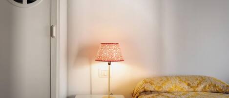 A bedroom with a bedside table, a lamp, and a bed with patterned bedding.